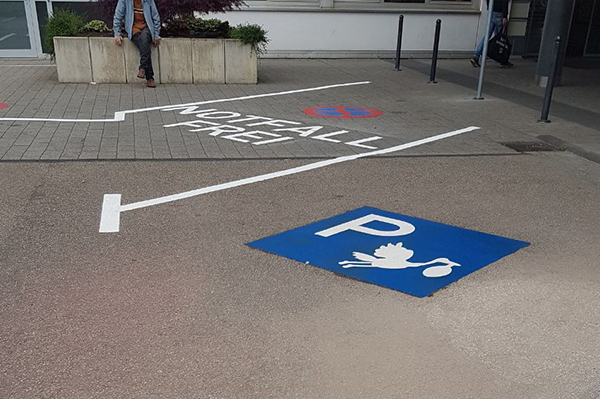 Área de estacionamiento con marcación azul y una cigüeña